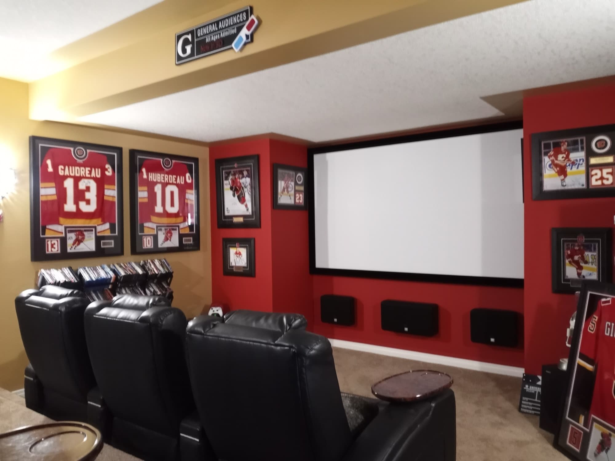 Calgary basement theatre with a projection screen, in-wall surround speakers and tiered seating